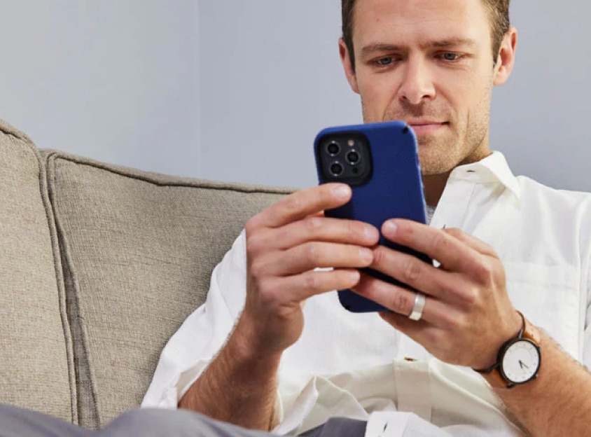 Mężczyzna siedzi na kanapie i spogląda na telefon